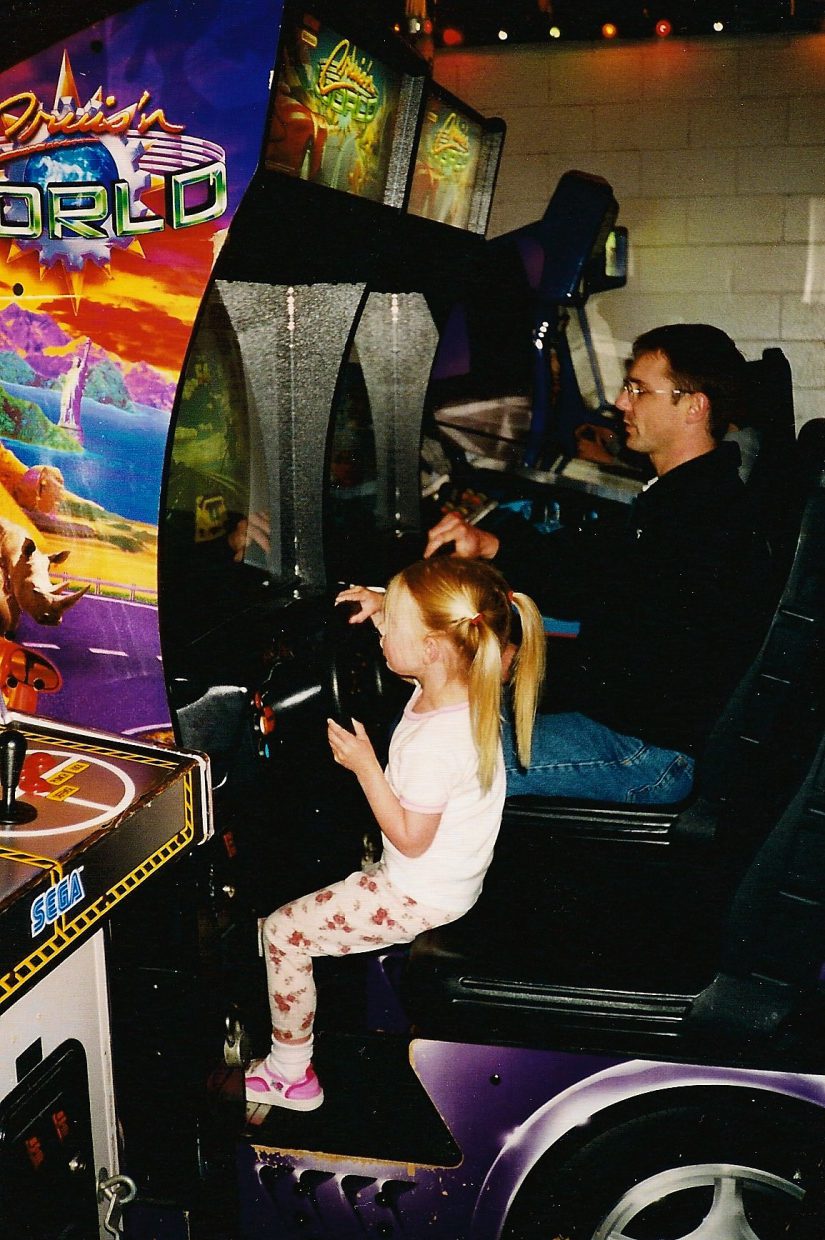 A young Holly and her dad are playing racing arcade games