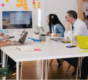 Team sitting around a table looking at a shared screen in a meeting