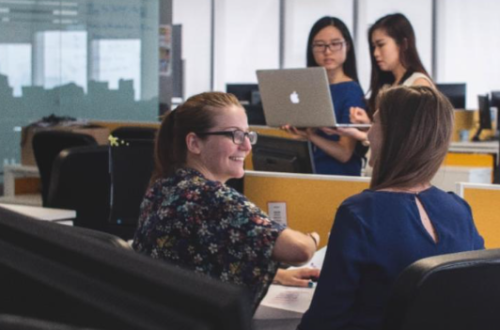 Office work place with people talking in the foreground and background